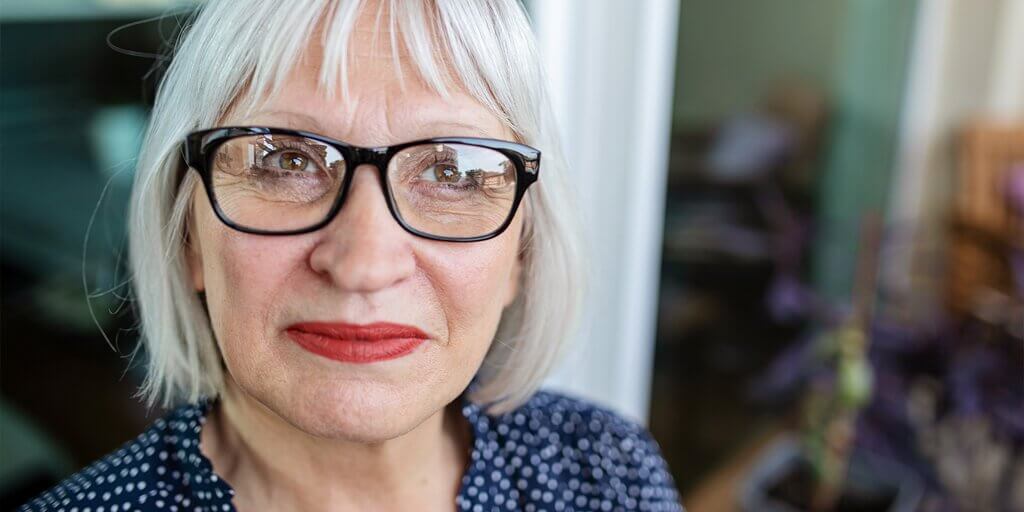 Aging Eye at a Glance A senior woman wearing eyeglasses and smiling at the camera.
