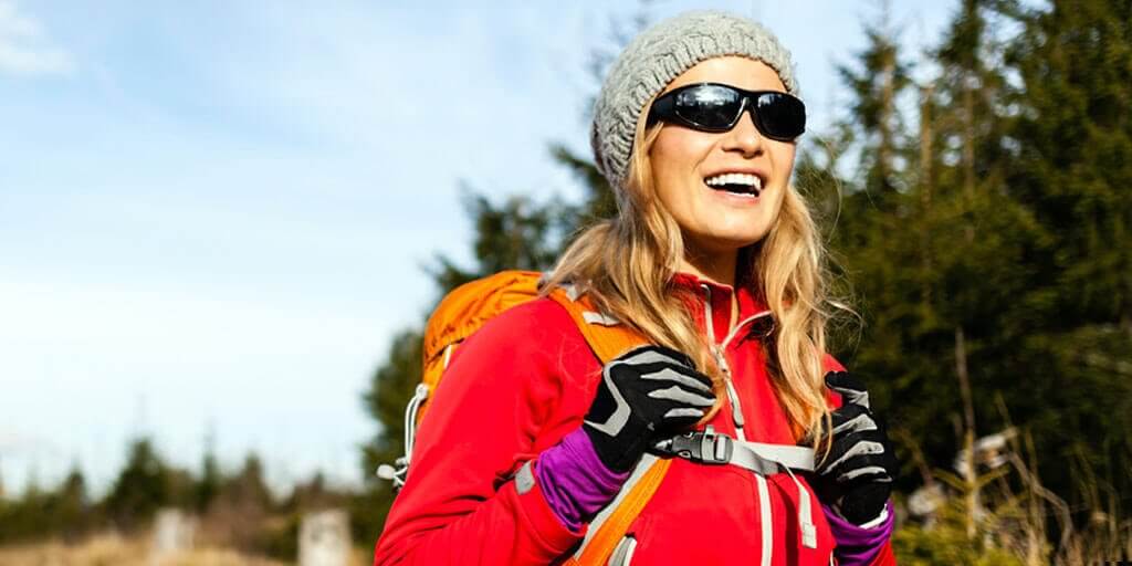 LASIK-at-a-glance A middle-aged woman wearing sunglasses, hiking outdoors in fall.